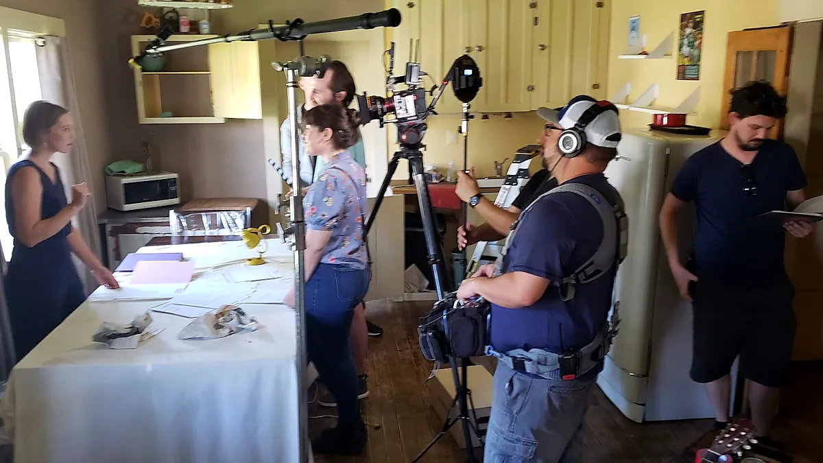 Production sound mixer, camera operator and lighting crew filming inside a home