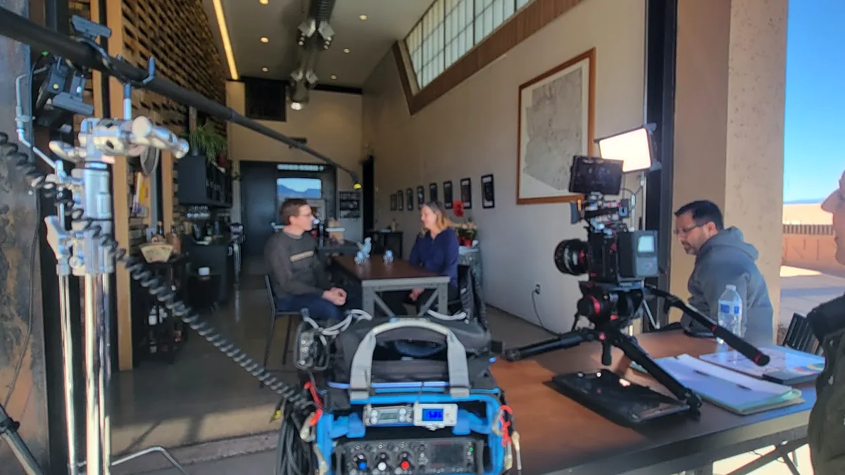 Interview production crew operating camera, lighting and field audio at a client location