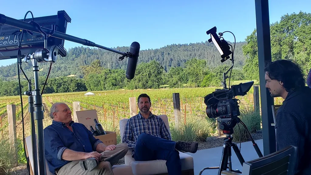 On-location interview beside a vineyard with professional camera, lighting and boom microphone