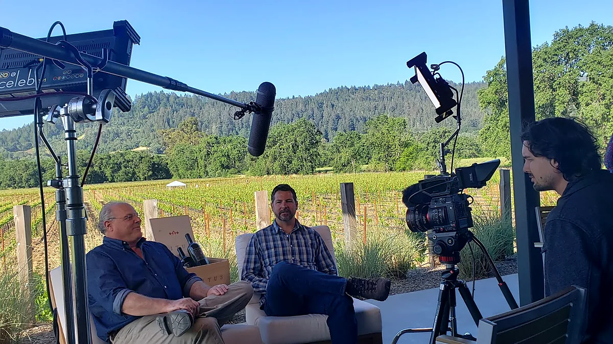 On-location interview beside a vineyard with professional camera, lighting and boom microphone