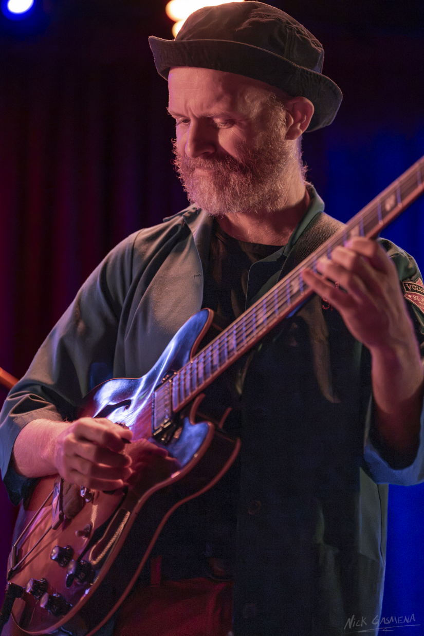 Ilan Smilan plays a hollow-body electric guitar under warm and blue stage lights at The Rosetta Room in Mesa.