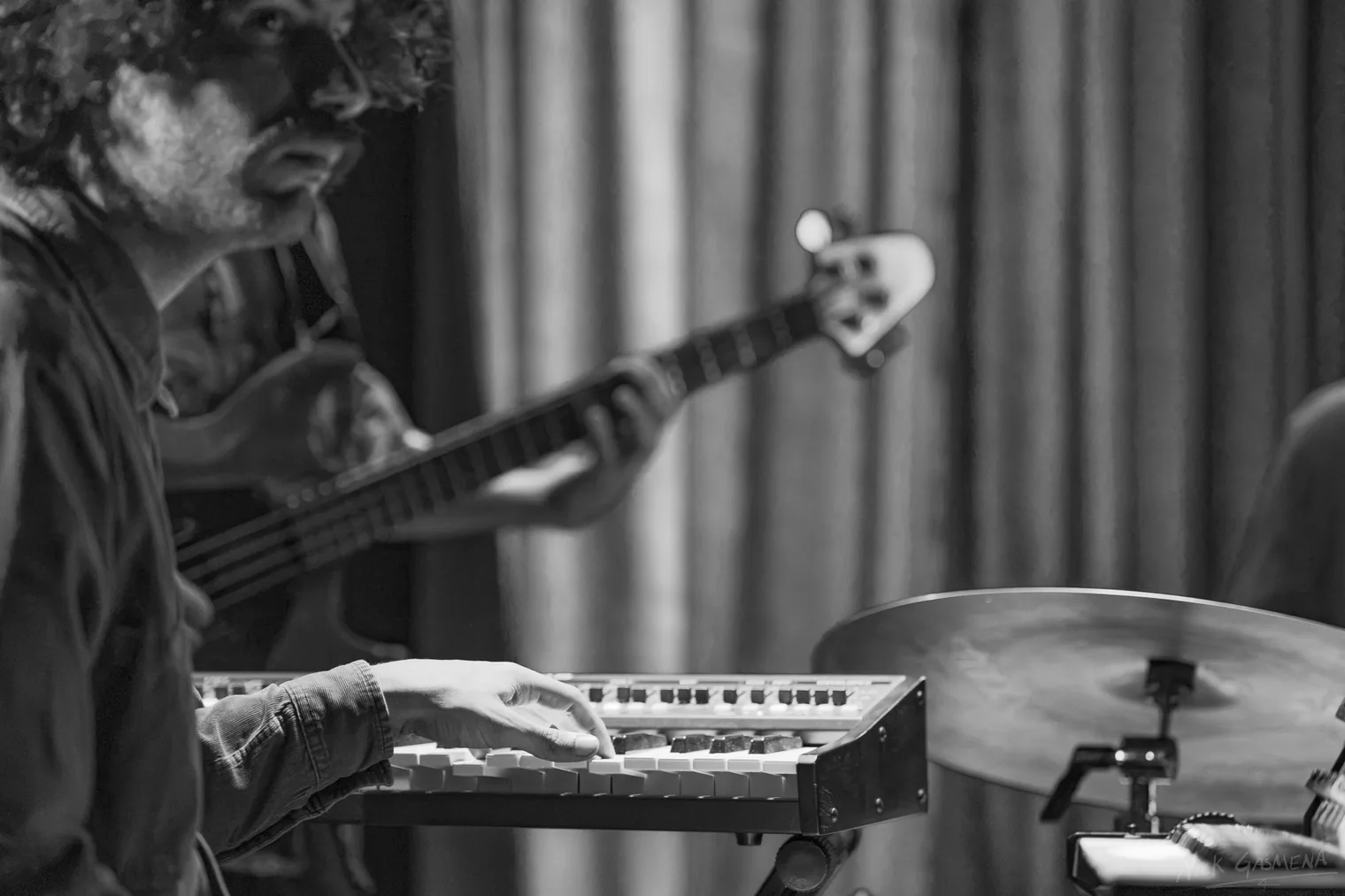 Black-and-white photograph of a bass guitarist and a keyboard player performing side by side.
