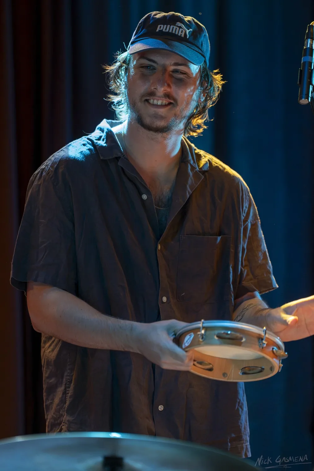 Itamar Weinstein holds a tambourine and smiles, wearing a baseball cap.