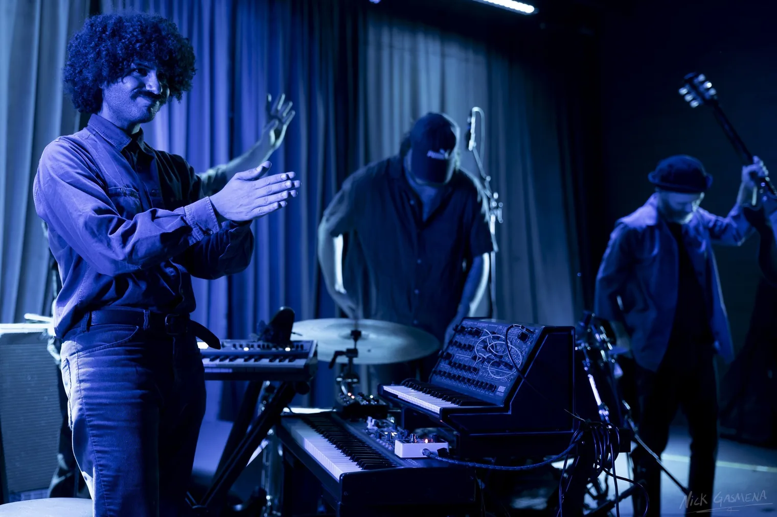 Sababa 5 perform under blue stage light, the keyboard player raising both hands.