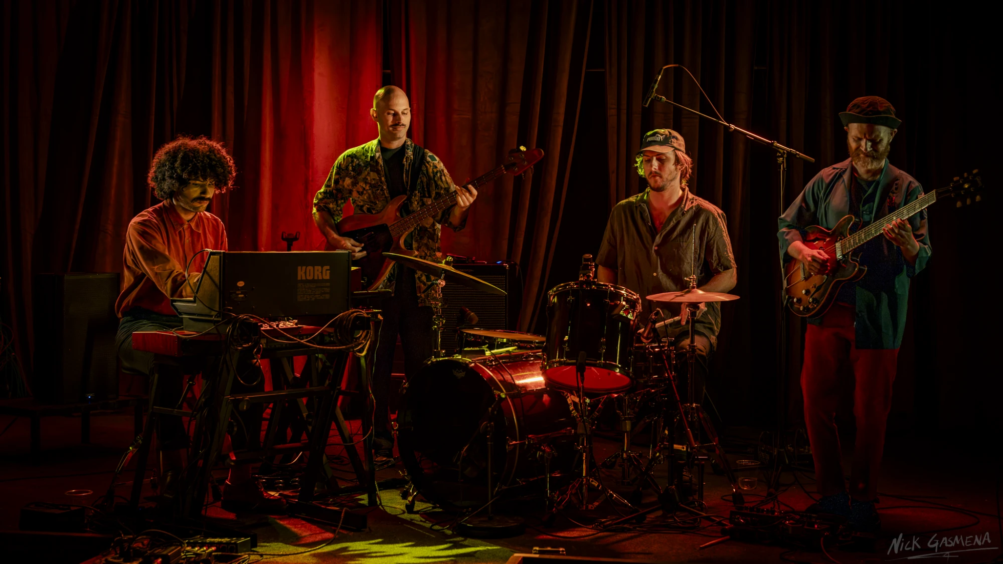 Sababa 5 on stage at The Rosetta Room in Mesa, keys, bass, drums and guitar lined up against a red curtain