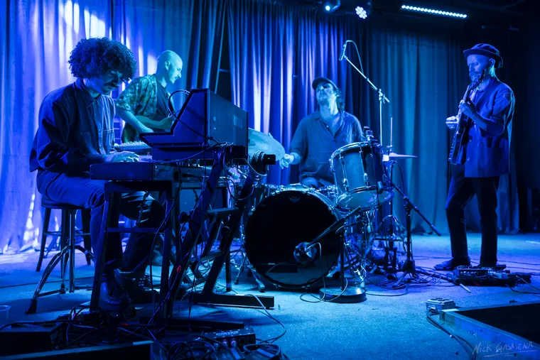 Sababa 5 on stage washed in blue light, Eitan Drabkin at the keys, Amir Sadot on bass, Itamar Weinstein at the drums and Ilan Smilan on guitar